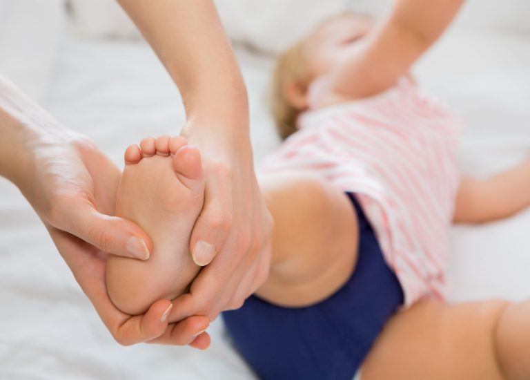 Baby girl receiving massage from mother at home